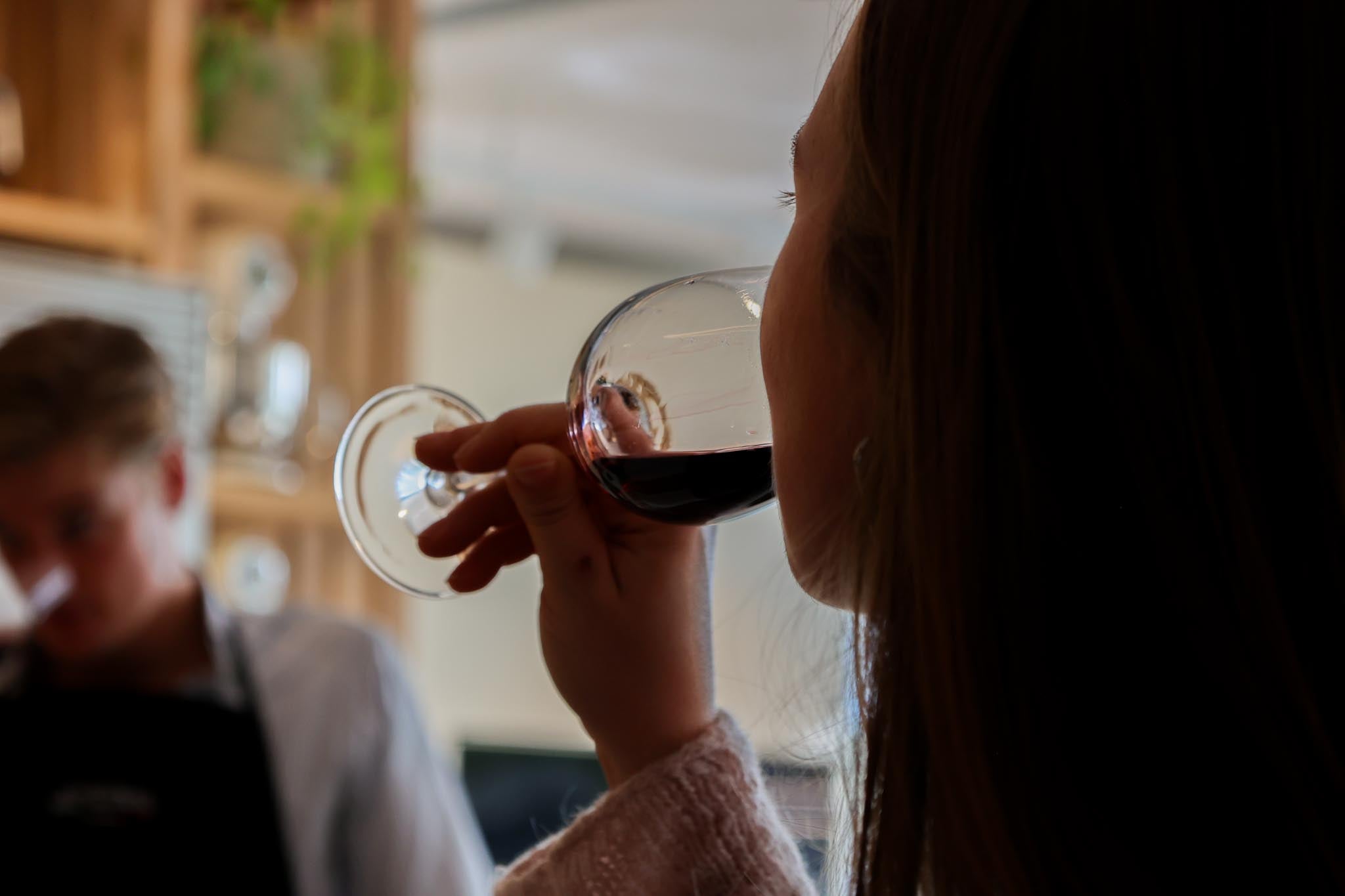 Guests comparing two glasses of red wine in a bright showroom